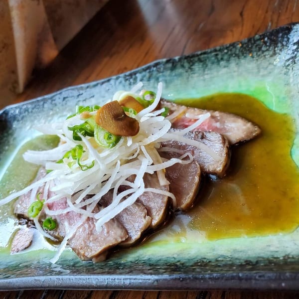 Thinly sliced meat with shredded white radish, green onions, and mushrooms in a savory sauce.