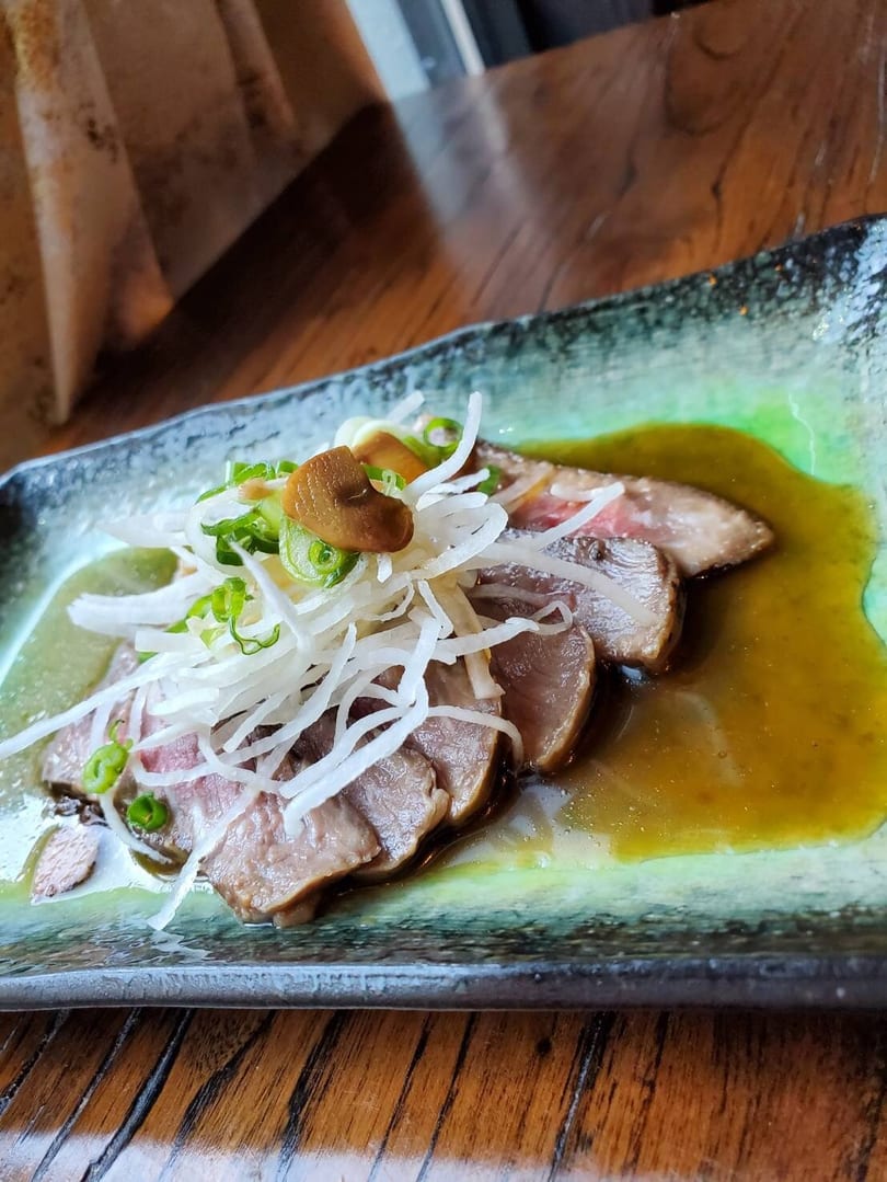 Thinly sliced meat with shredded white radish, green onions, and mushrooms in a savory sauce.