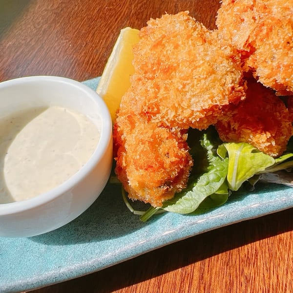 Crispy fried oysters with a lemon wedge, lettuce, and a side of creamy dipping sauce.