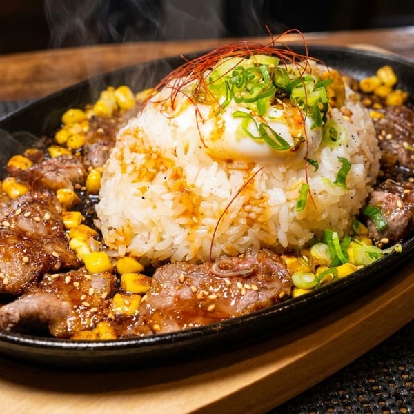 Steaming hot sizzling plate with rice, beef, corn, a poached egg, and green onions.